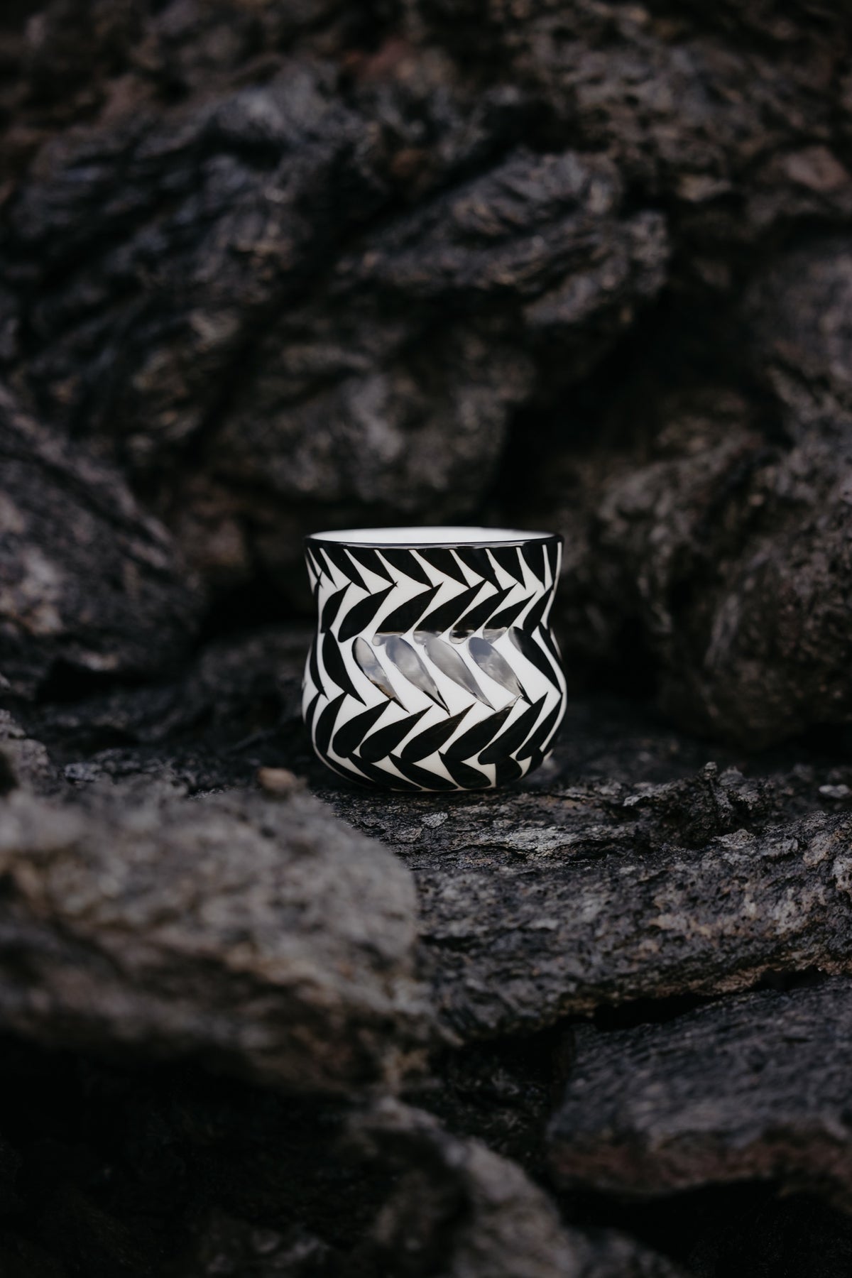Black and white hand-painted porcelain cup on volcanic rock in Grindavík, Iceland.